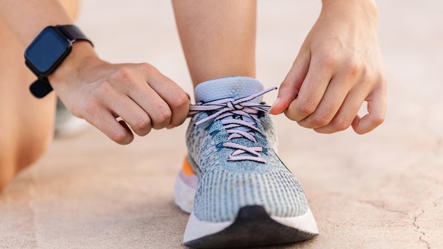 Close-up view of female jogger hands tying laces of her sport shoes before running exercise routine. Motivation, healthy lifestyle and fitness concept. 