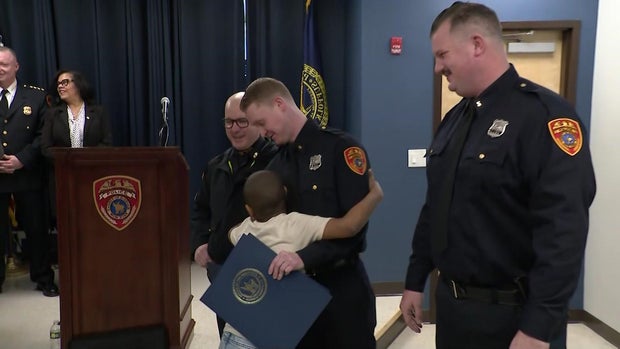 A child hugs a Suffolk County police officer as two others watch 