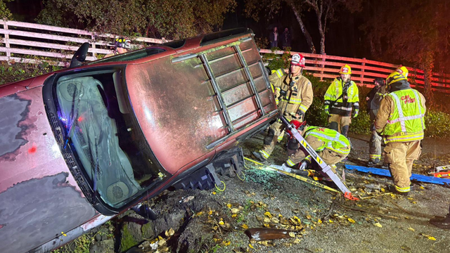 Emergency crews near a car that is flipped on its side 
