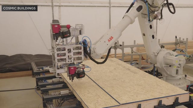 A robotic arm builds a plywood panel 