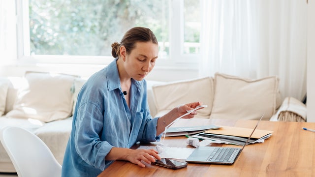 Woman looking through bills and documents from insurance company and looking worried 