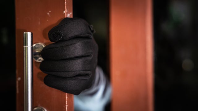 dangerous masked burglar with crowbar breaking into a victim's home door,Home insurance concept 