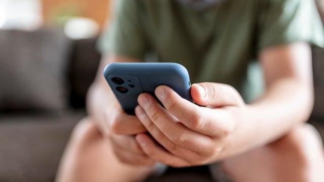 teenager boy is using smartphone at home - home schooling 