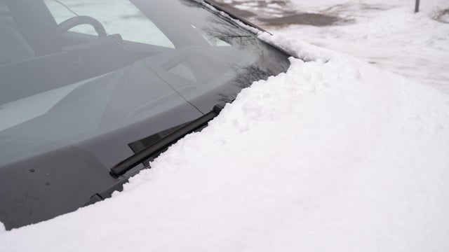 Windshield wipers of a car parked on the street covered with snow  in winter. 