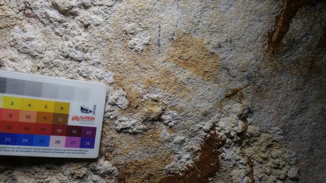 The faint image of a hand stencil that has been dated to 67,800 years ago is seen in a limestone cave called Liang Metanduno on Muna 