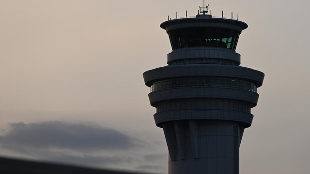 An Air Traffic Control Tower overlooking evening arrivals and departures at a busy urban airport 