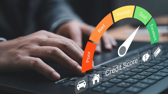 Close-up of hand typing on a laptop with a credit score gauge displayed. The gauge indicates varying levels of credit quality from poor to excellent for highlighting the importance of financial health 