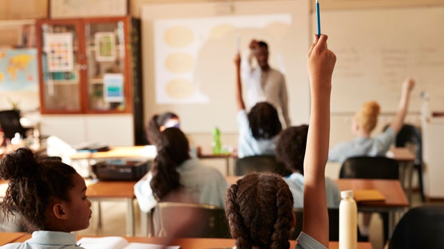 Back view of a female professor teaching her students at lecture hall. 