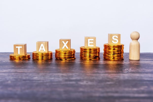Taxes written on wooden block with stacked coins 
