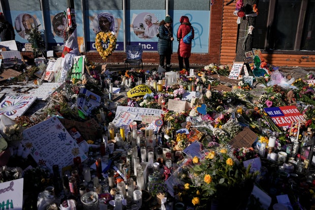 Flowers, candles and signs left by mourners at a memorial for Alex Pretti 