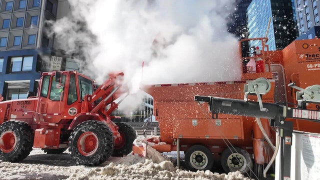A front-loader drops snow into a snow-melter 