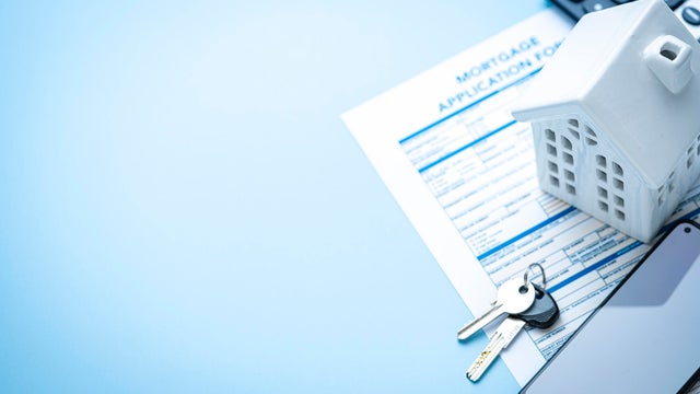 Flat lay of real estate concept. Mortgage application form, house model, house keys and mobile phone with blank screen. Copy space 