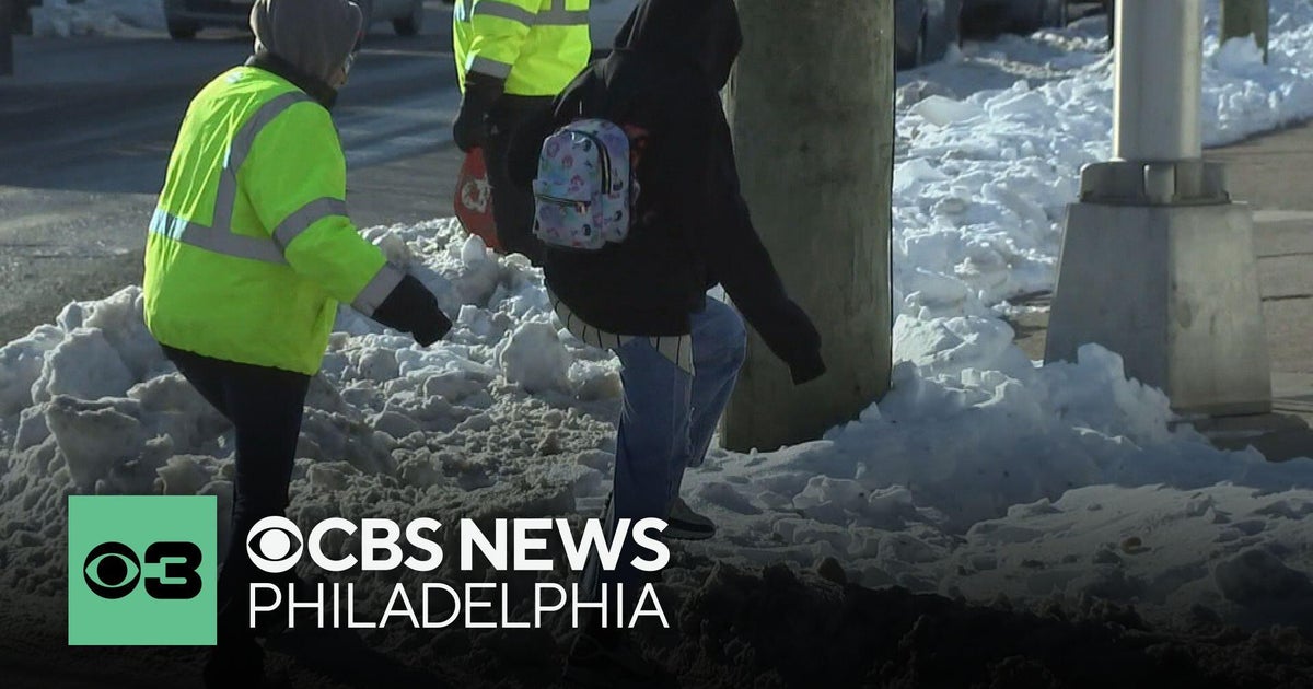 Gloucester City, New Jersey, crossing guards help students cross piles of snow at busy intersection