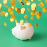 Financial freedom concepts still life -  gold coins flying on top of piggy bank. 