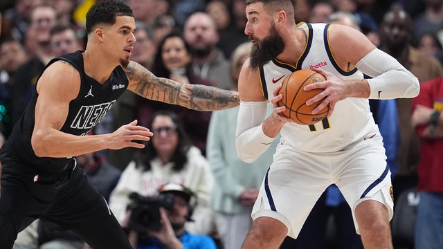 Denver Nuggets center Jonas Valančiūnas, right, looks to pass the ball as Brooklyn Nets forward Michael Porter Jr. defends in the first half of an NBA basketball game, Thursday, Jan. 29, 2026, in Denver. 