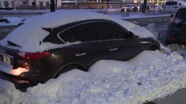Car parked on street covered in snow 