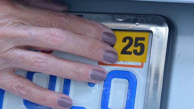 Annual registration sticker being applied to license plate 