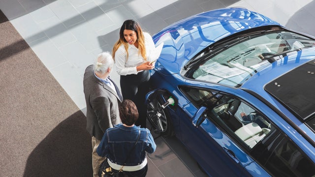 High angle view of saleswoman showing car to customers at showroom 