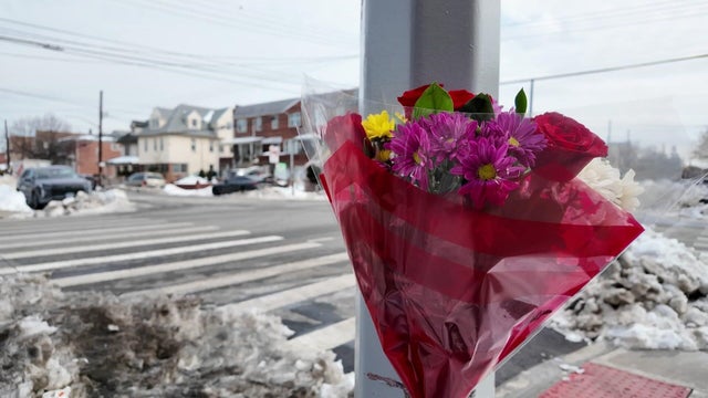 Flowers tied to a streetlight pole at a corner 
