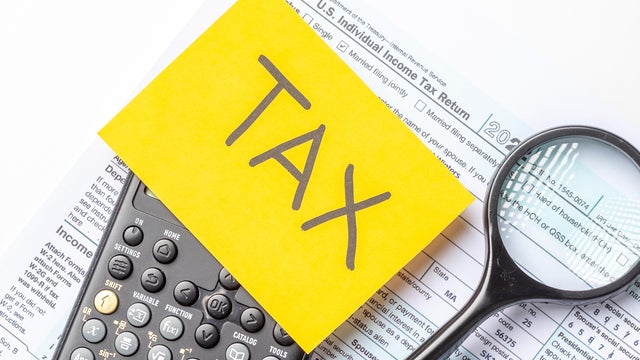Tax preparation tools on a desk with a calculator and tax forms during filing season in a home office setting 