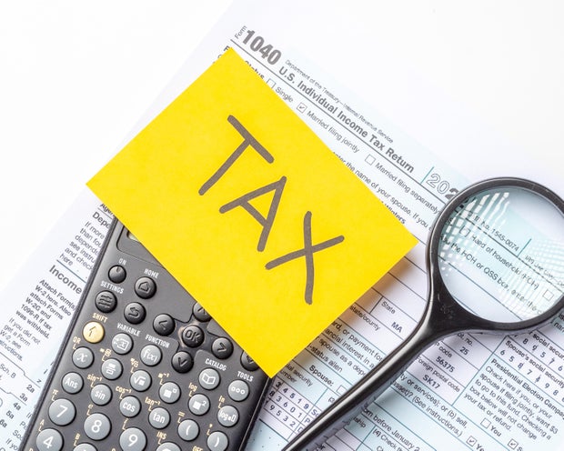 Tax preparation tools on a desk with a calculator and tax forms during filing season in a home office setting