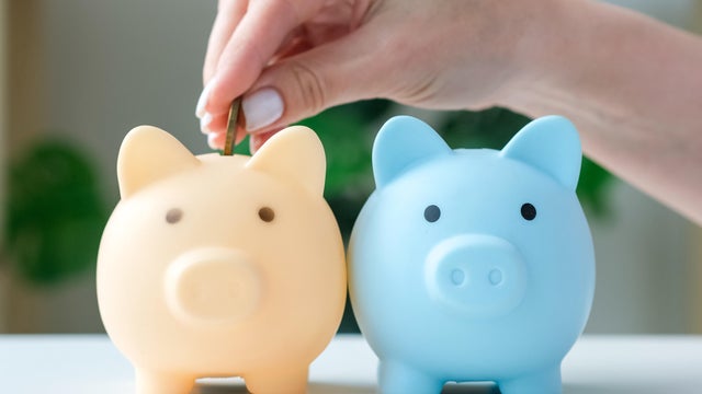Female hand throws coins in two piggy banks in turn. Pension, savings, finance accounting diversification 