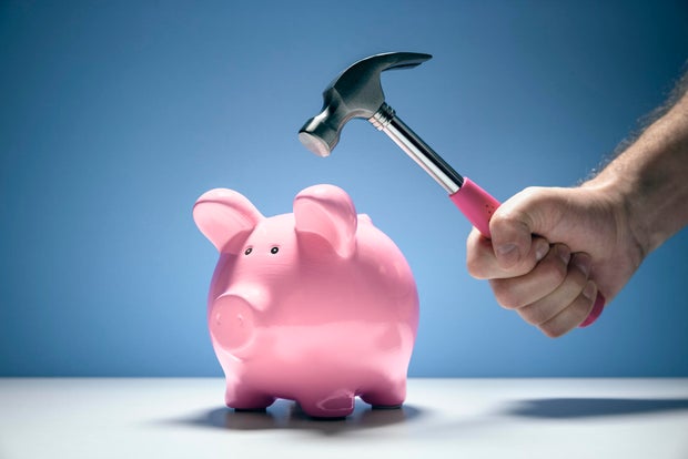 Piggy bank and hand with hammer about to smash to get at savings