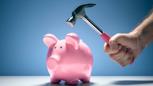 Piggy bank and hand with hammer about to smash to get at savings 
