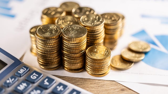 Pile of golden fifty cent euro coins with financial graph and calculator. Concept of economy, financial growth and banking. 
