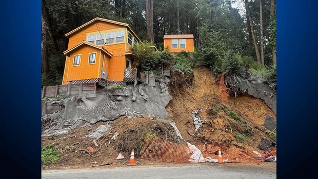 House seen above a dirt hillside that has partially been covered with cement 