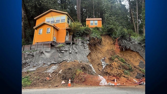 House seen above a dirt hillside that has partially been covered with cement 