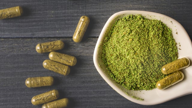 Top view of Kratom powder in ceramic spoon and Kratom capsules 