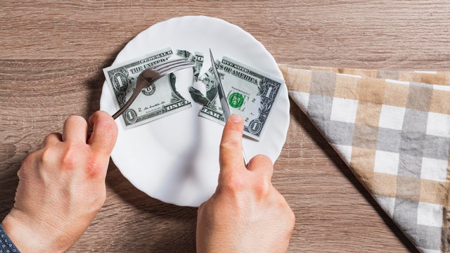 Hands of unknown person cutting banknote 