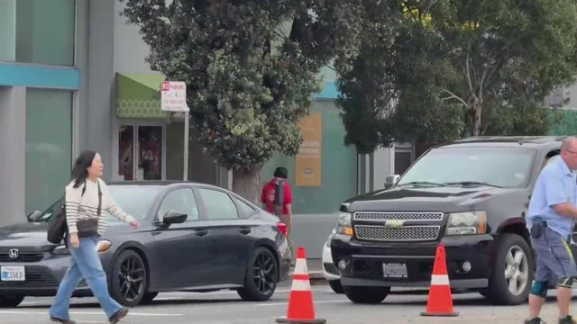 Vehicles stopped at an intersection as people cross the street 