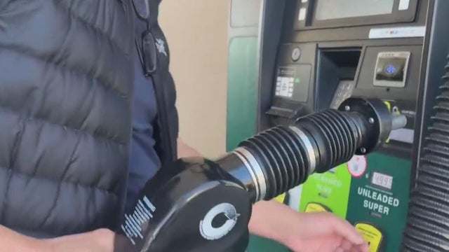A man holds a gas pump handle 