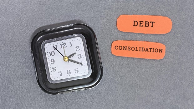 Debt consolidation concept with clock and notes on gray background 