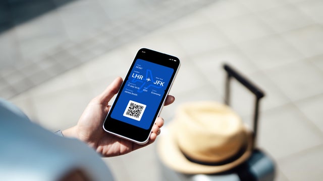 Close-up of female hand holding smart phone with boarding pass 