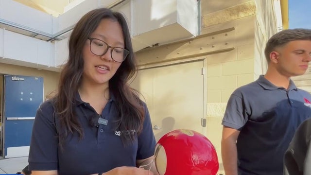 a high school student holds a fire-retardant device that is part of a wildfire suppression system 