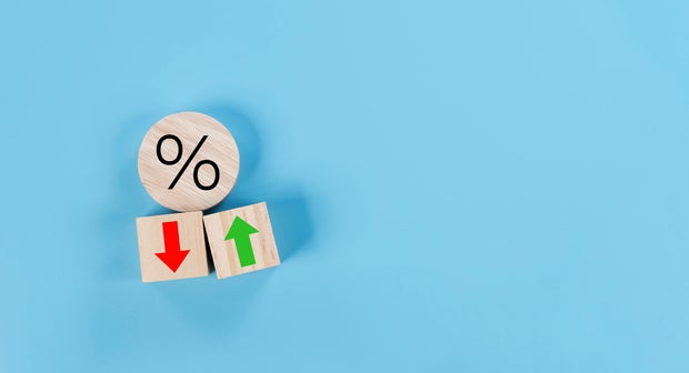 Percentage icon on wooden cube block and up and down arrow symbol on flipping white dice on blue background 