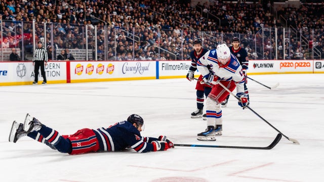 Dylan DeMelo #2 of the Winnipeg Jets dives and pokes the puck from Alexis Lafreni&egrave;re #13 of the New York Rangers in the third period at Canada Life Centre on March 12, 2026 in Winnipeg, Canada. 