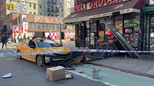 A taxi with front-end damage and a building damaged after a crash 