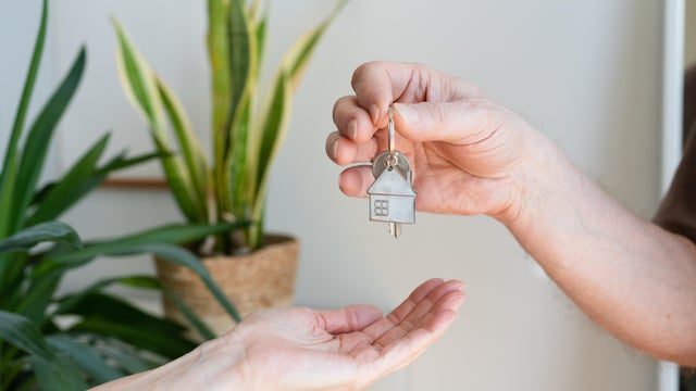 Man&acute;s hand giving the keys of a house to a new home owner 