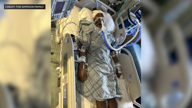 Justin Simpson lying in hospital bed 