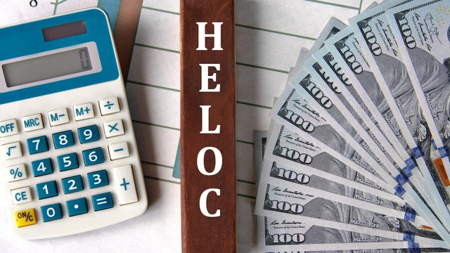 HELOC - word on brown wooden blocks on the background of a graph and banknotes 