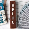 HELOC - word on brown wooden blocks on the background of a graph and banknotes 