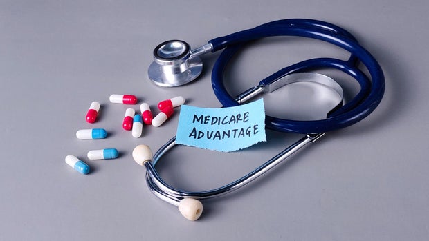 Medicare Advantage Concept with Stethoscope, Note, and Capsules on Gray Background 