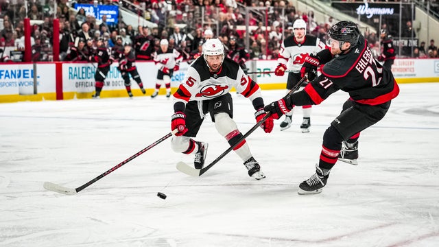 Nikolaj Ehlers #27 of the Carolina Hurricanes against Brenden Dillon #5 of the New Jersey Devils during the first period at Lenovo Center on March 28, 2026 in Raleigh, North Carolina. 
