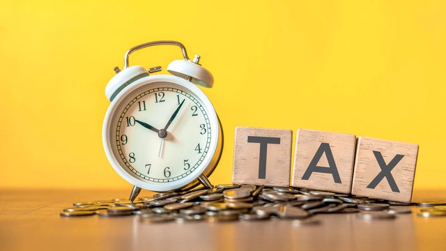 Tax text written on wooden block with stacked coins 