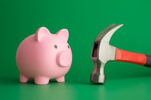 Pink piggy bank face to face hammer on green background. 