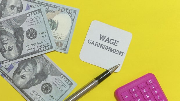 Wage garnishment documents with money and calculator on yellow background